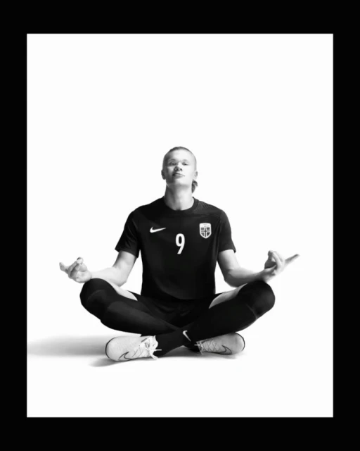 Monochrome image of a blonde soccer player in athletic wear sitting cross-legged with a serene expression, symbolizing focus and balance.
