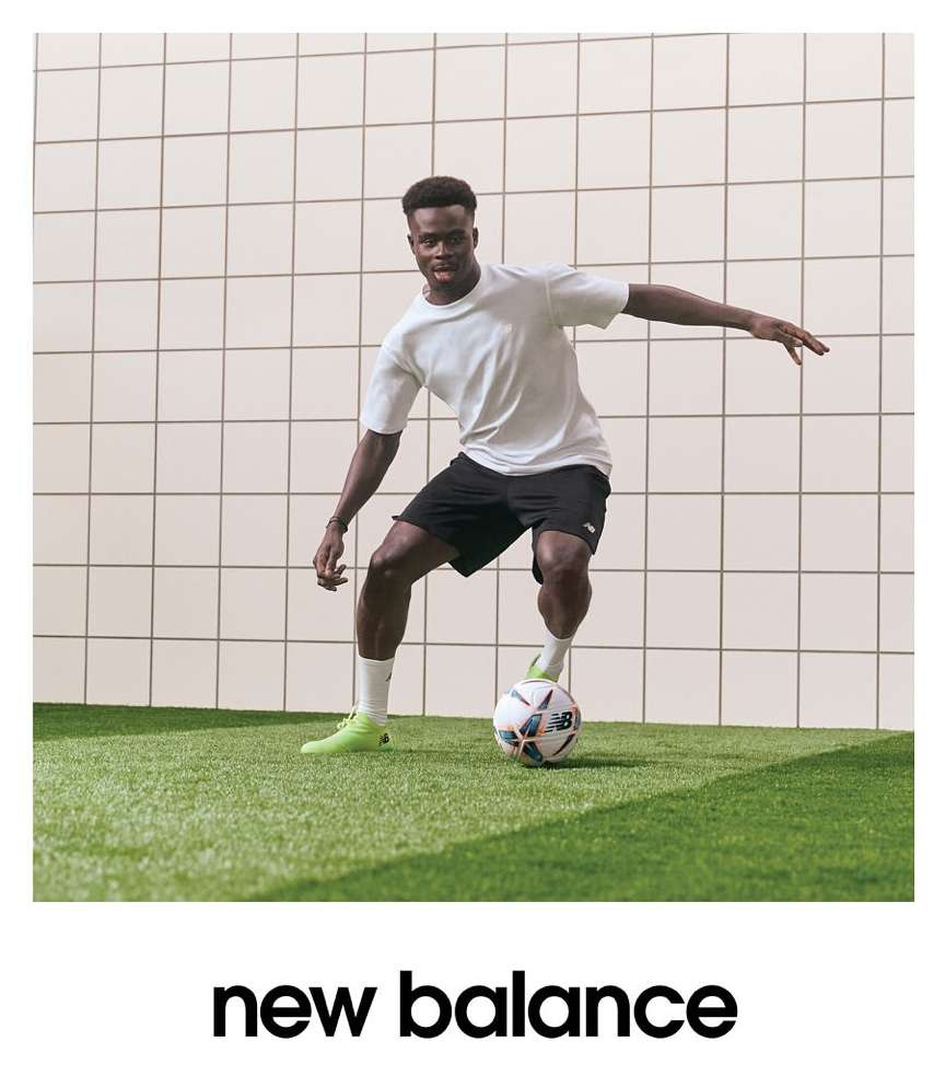 Athletic Black male soccer player in sportswear showcasing a soccer ball on a green field against a gridded white background inside.
