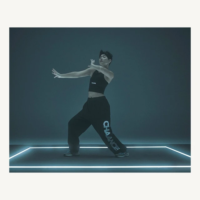 Male dancer in dark athleisure wear poses expressively against a dark backdrop with glowing lines. Modern dance and fashion concept.
