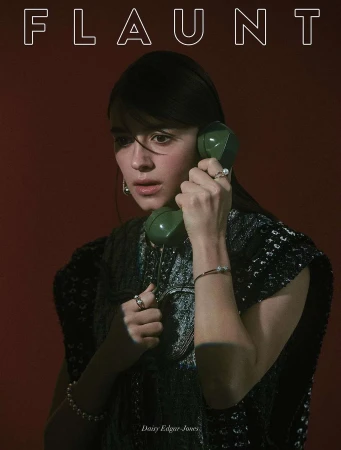 Close-up portrait of Daisy Edgar-Jones holding a vintage green rotary phone, wearing a dark textured sleeveless top with pearl jewelry.