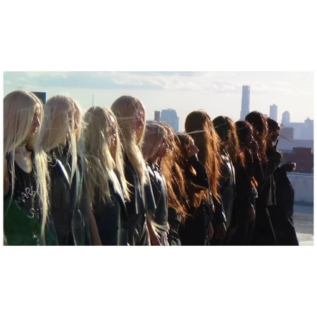 A line of models with long blonde hair standing on a rooftop against a city skyline by Carlota Guerrero.
