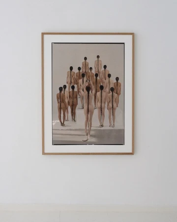 Artistic photograph of a framed print depicting a group of nude figures, seen from behind, with hair braided down their backs.