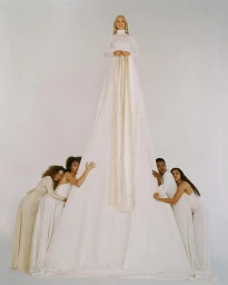Group of five models in white garments forming a pyramid shape with one person standing at top by Carlota Guerrero