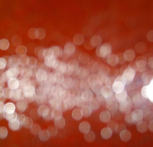Blurred photo of bokeh lights with a red-orange background, creating an abstract and visually interesting pattern.