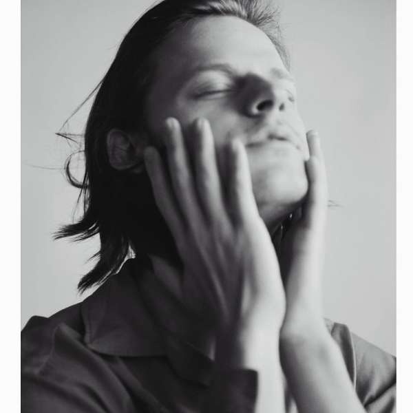 Portrait of a man holding his face with hands raised upward by Carlotta Manaigo