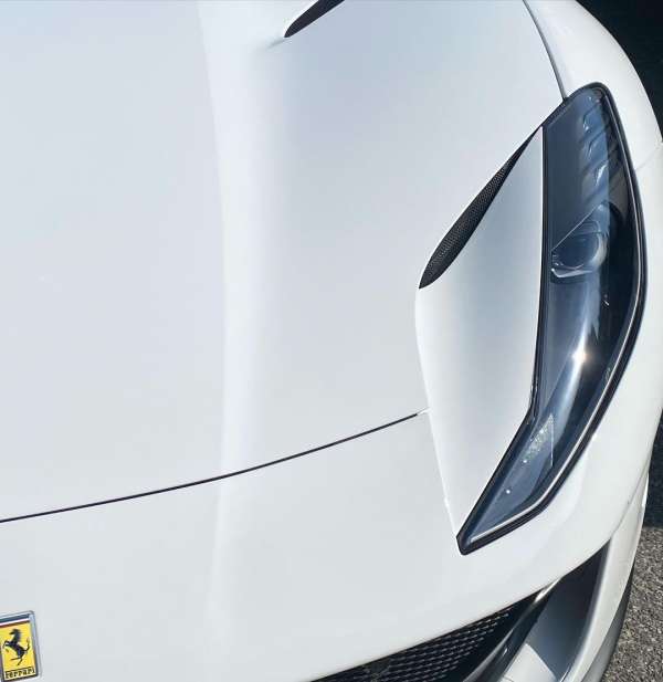 Close-up shot of a white luxury sports car highlighting the sleek headlight design and hood contour.