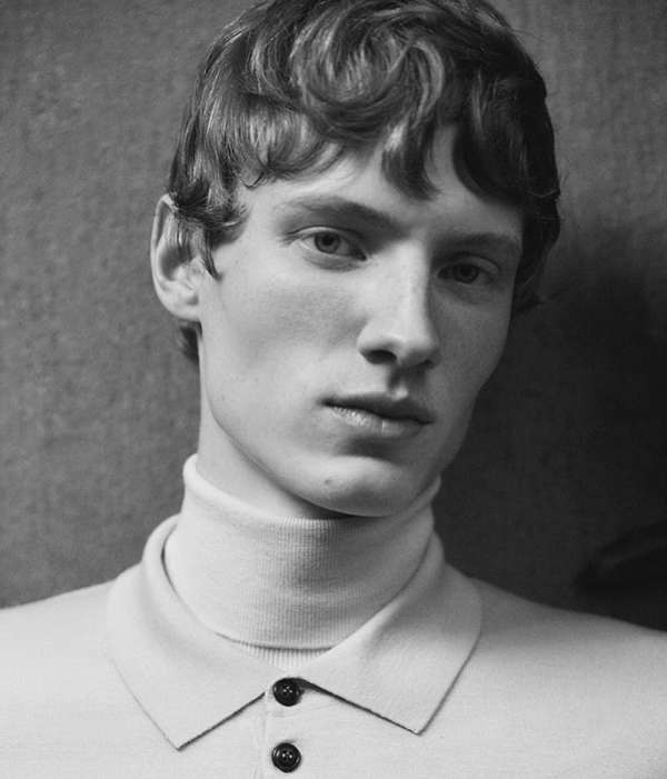 Black and white portrait of a fair-skinned adult male with wavy light brown hair, wearing a light-colored turtleneck shirt, indoors.