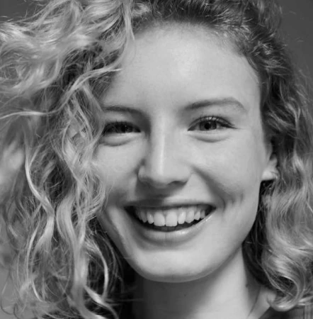 Close-up monochrome portrait of a smiling young woman with curly blonde hair by Carlotta Manaigo