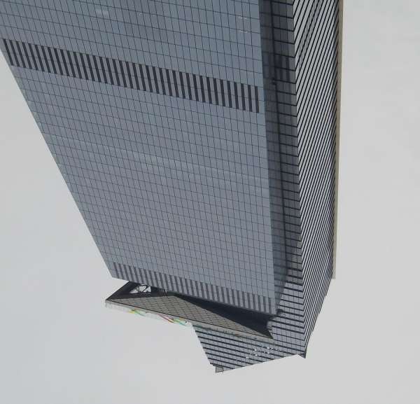 Low angle view of the angular, glass-clad Bank of America Corporate Center skyscraper against a light sky in Charlotte, NC.