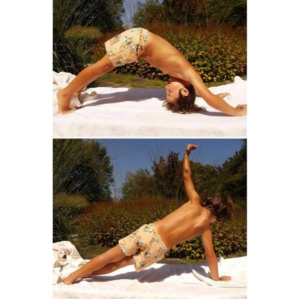 Child with dark hair performing yoga poses on a white blanket outside with green trees and blue sky as background.