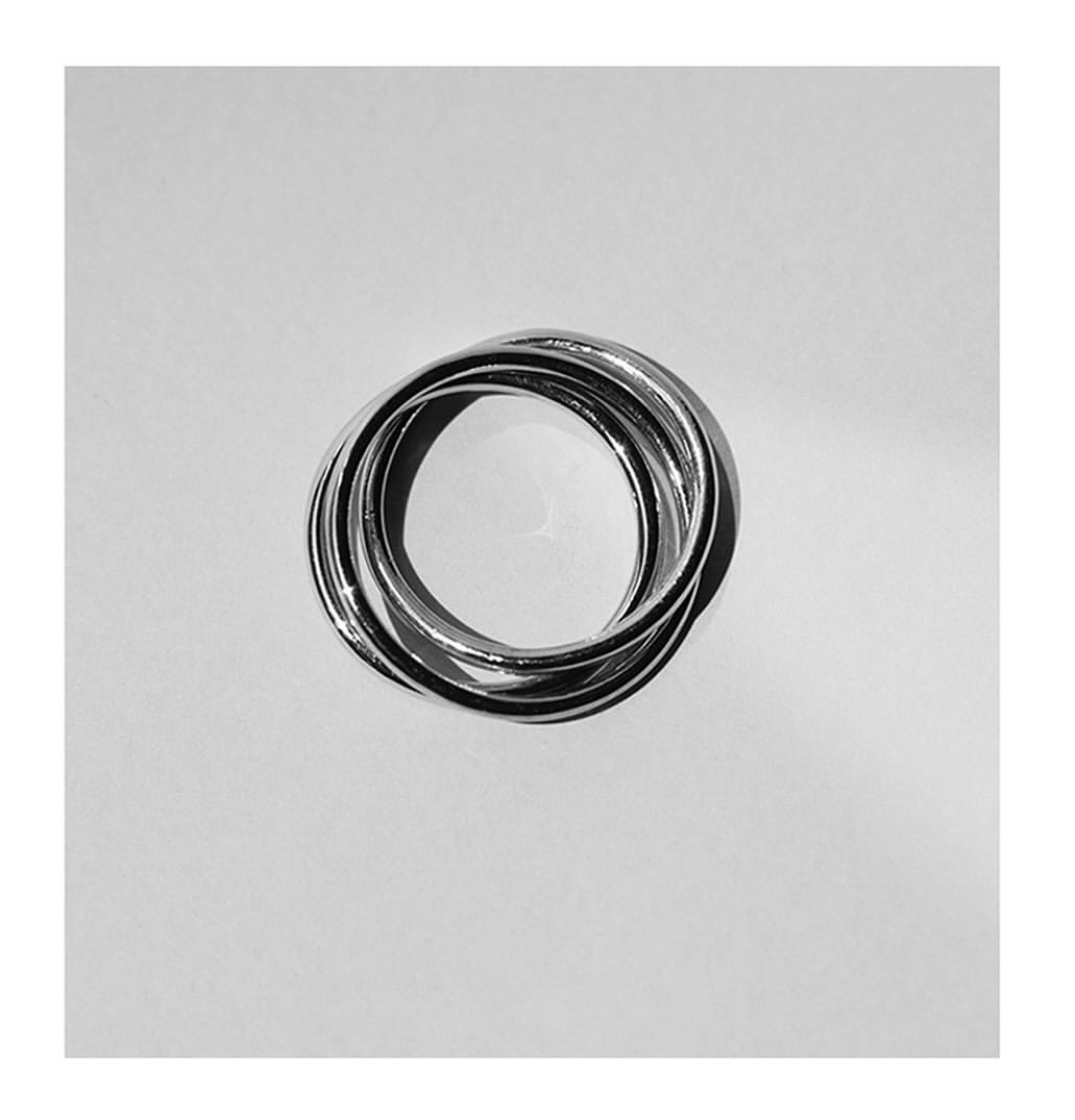 Close-up studio shot of interconnected silver rings on a neutral background, showcasing shiny texture and minimal aesthetic.