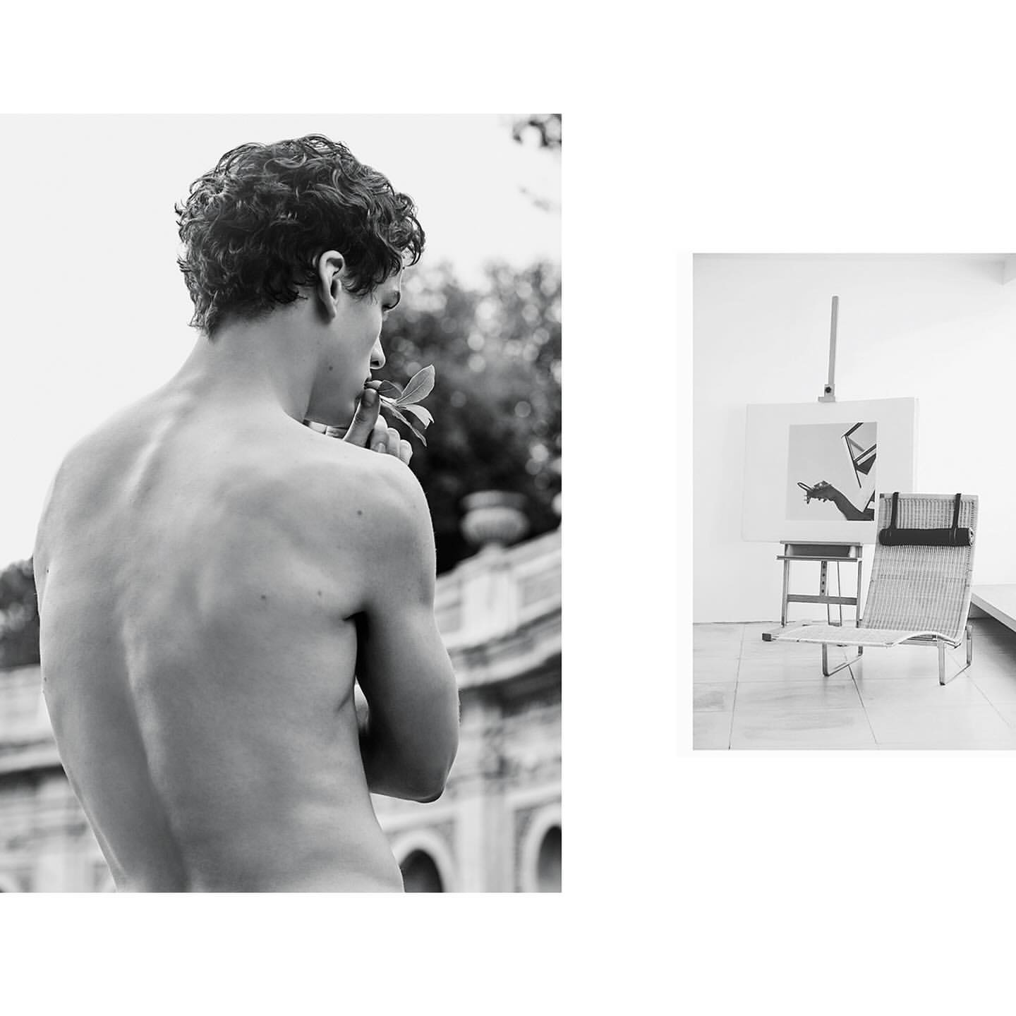 Black and white portrait of a shirtless young man holding leaves, with an easel and lounge chair visible
