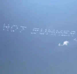 Skywriting spelling out the words HOT SUMMER against a clear blue sky