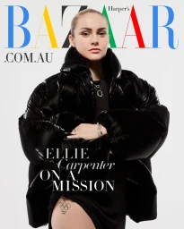 Portrait of professional soccer player Ellie Carpenter wearing a glossy black puffer jacket against a white background