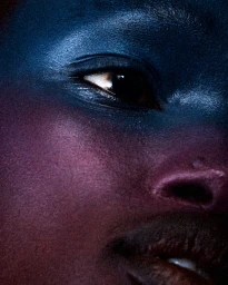 Extreme close-up of a face featuring dramatic blue and purple metallic eye and cheek makeup by Kristyan Low.