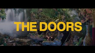 A scenic background with dense vegetation, a waterfall, and the title "THE DOORS" prominently displayed in yellow letters.