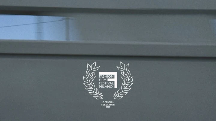 Fashion Film Festival Milano logo on a gray textured background with horizontal lines, an official selection emblem for 2020.