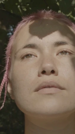 Close-up portrait of a woman with pink hair and braids outdoors in natural light by photographer Caroline Mackintosh