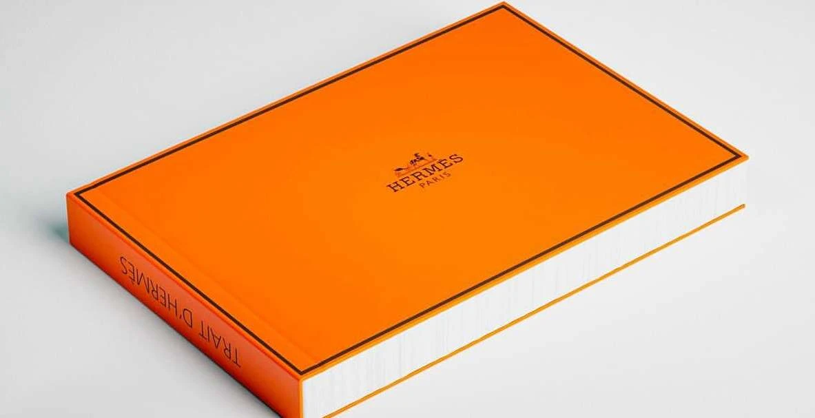 Orange Hermes Paris book on a white surface, product shot. Close-up view, displaying its cover and brand logo on a white background.