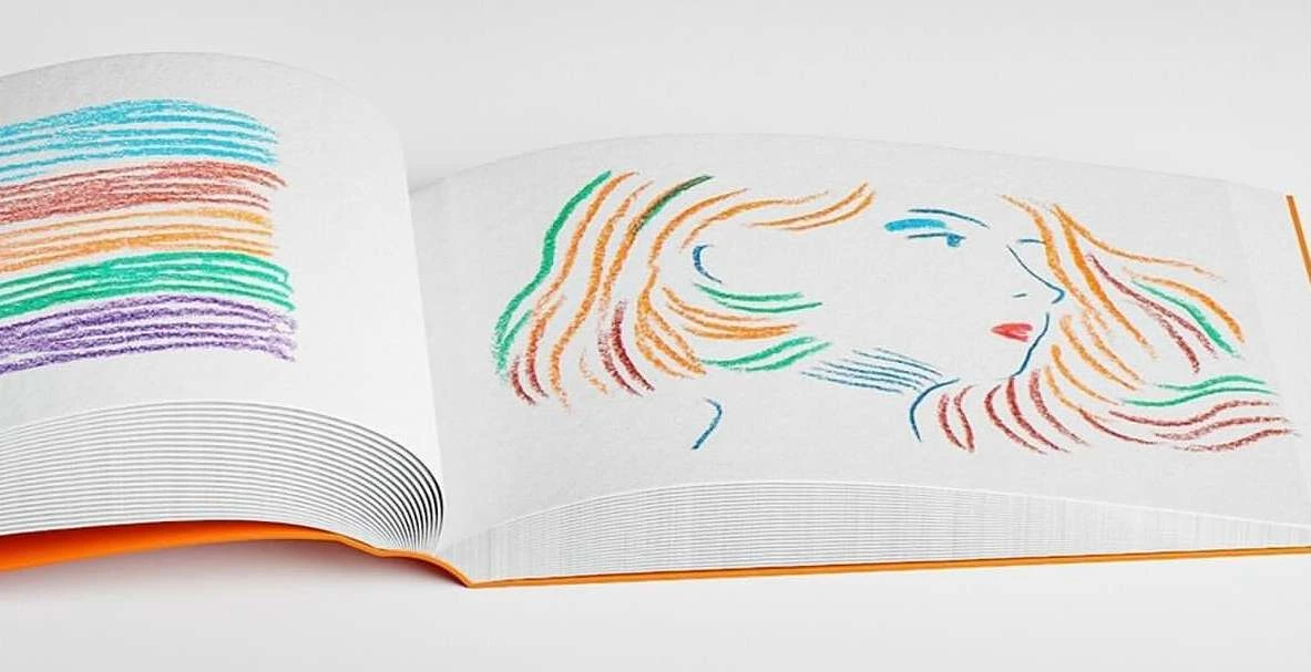 Open book displays colorful drawing of a woman's profile along with stripes in crayon on white paper with a bright orange spine.
