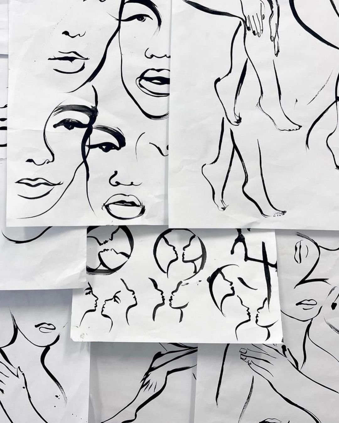 Line art drawings on white paper featuring faces, bodies, and silhouettes, creating an artistic and graphic composition.