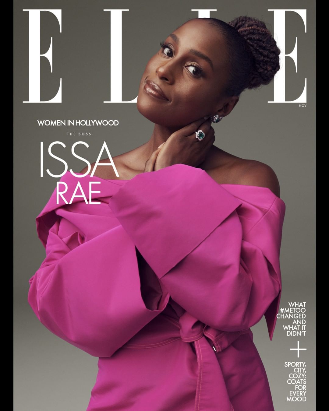 Issa Rae graces the cover of Elle Magazine in a pink off-the-shoulder dress, accessorized with a ring and earrings, against a gray backdrop.
