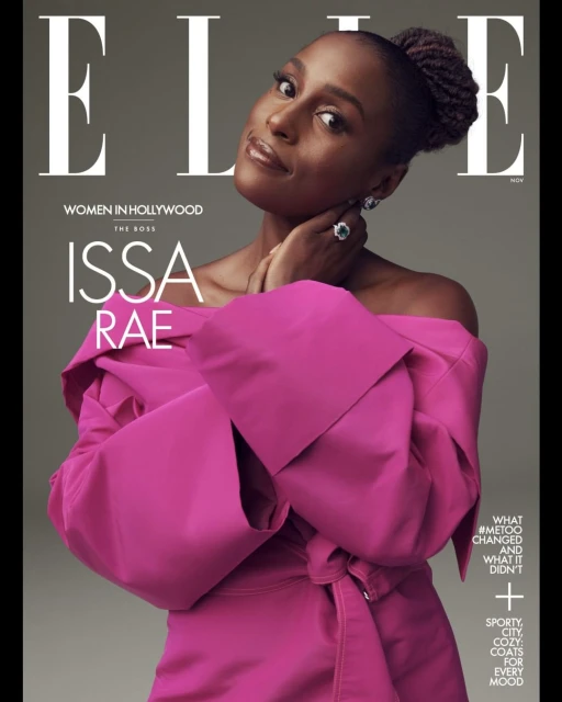 Issa Rae graces the cover of Elle Magazine in a pink off-the-shoulder dress, accessorized with a ring and earrings, against a gray backdrop.