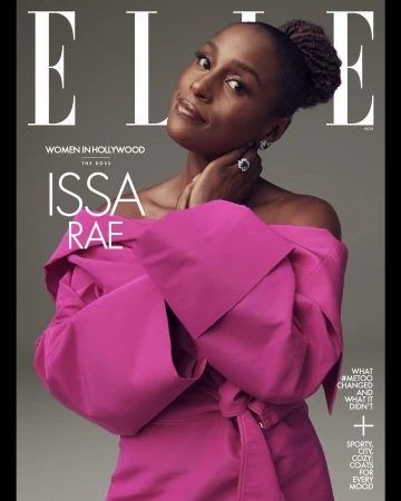 Issa Rae graces the cover of Elle Magazine in a pink off-the-shoulder dress, accessorized with a ring and earrings, against a gray backdrop.