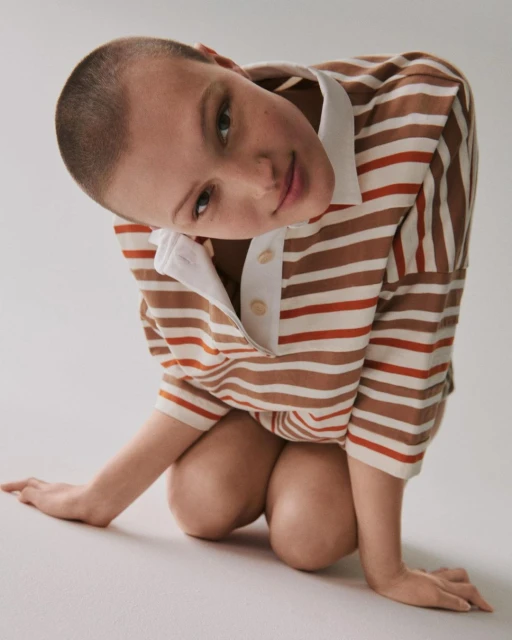 Woman in striped shirt with white collar poses in front of white background. Close-up shot of model in Fashion editorial.