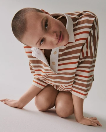Woman in striped shirt with white collar poses in front of white background. Close-up shot of model in Fashion editorial.
