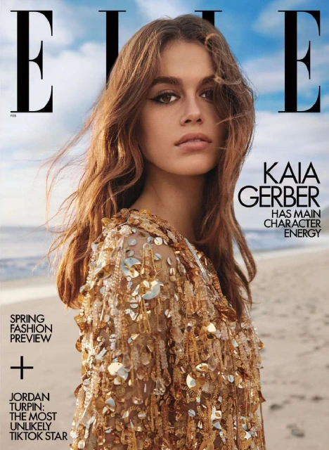 Elle magazine cover featuring model Kaia Gerber in a gold sequined top, set against a blurred beach and sky background. Fashion, beauty, editorial.