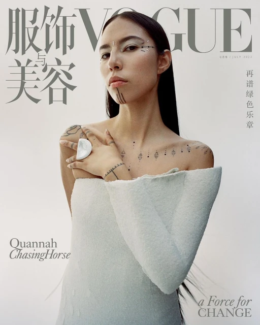 Vogue magazine cover featuring a young woman with decorative face and body markings, wearing a white textured dress against a white backdrop.