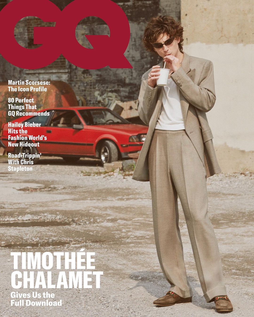 Timothée Chalamet on GQ magazine cover, wearing a beige suit and sunglasses, drinking from a white cup with a red car in the background.