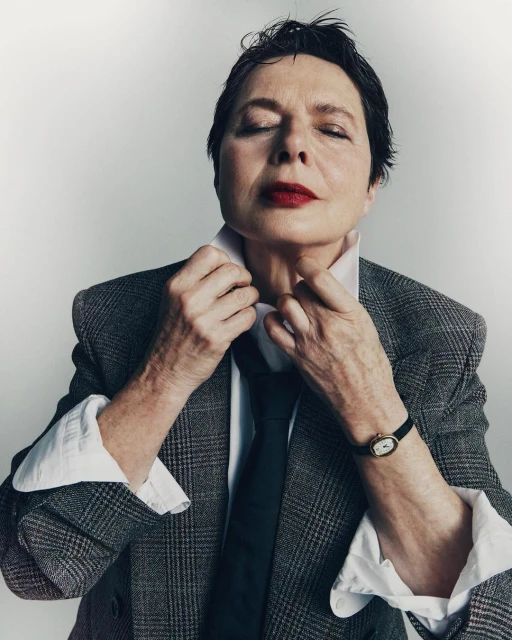 Stylish portrait of an adult female with closed eyes, dressed in a grey plaid blazer, adjusting her white shirt collar and black necktie.