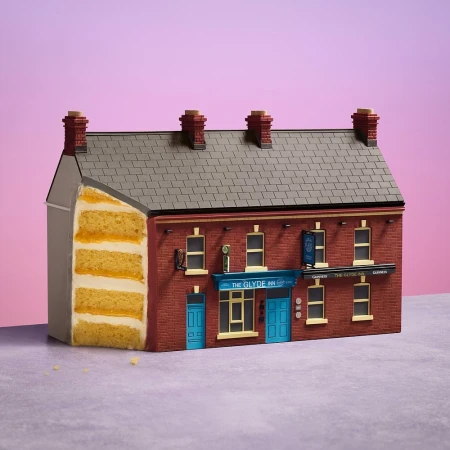 Novel architectural cake art depicting a detailed pub building facade featuring brickwork, windows, and signage against a pink background.