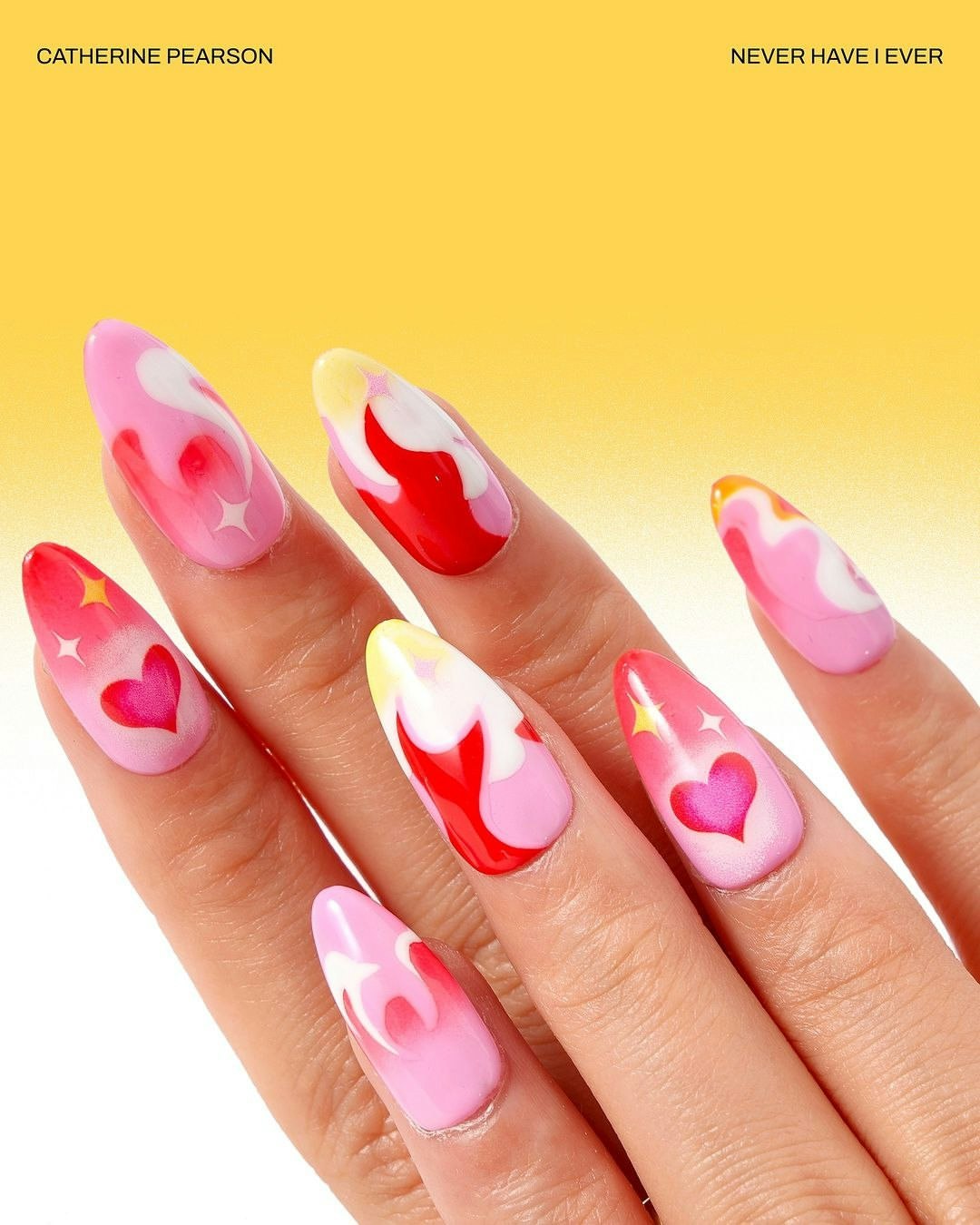 Close-up of a manicured hand showcasing long, almond-shaped nails with pink, red, yellow, and white abstract flame and heart designs.