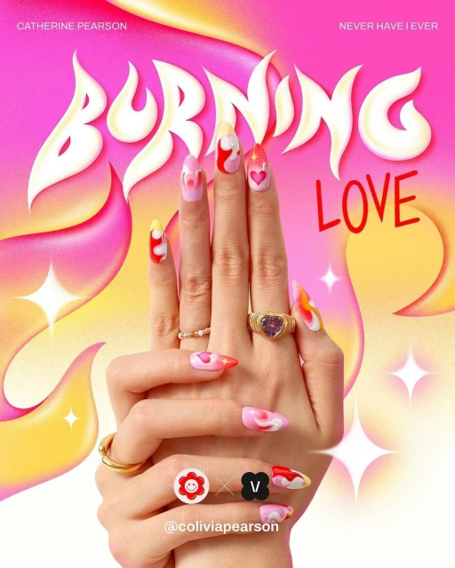 Close-up of hands with artistic nail art, featuring heart and flame designs, gold rings, and a pink and yellow abstract background.