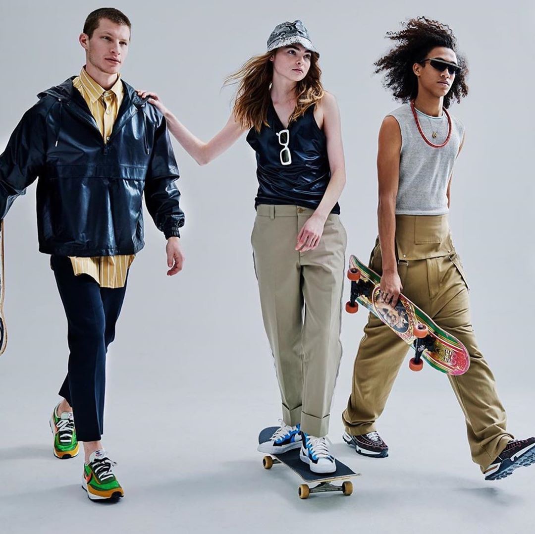 Three fashion models showcase streetwear while holding skateboards in a studio setting. A group of diverse individuals in modern clothes.