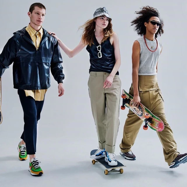 Three fashion models showcase streetwear while holding skateboards in a studio setting. A group of diverse individuals in modern clothes.