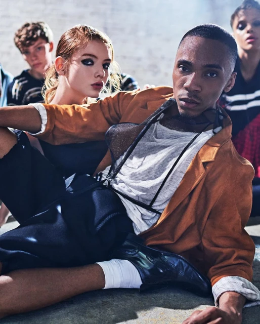 A group of young, diverse fashion models in a gritty studio environment, featuring both male and female models in casual modern clothing.