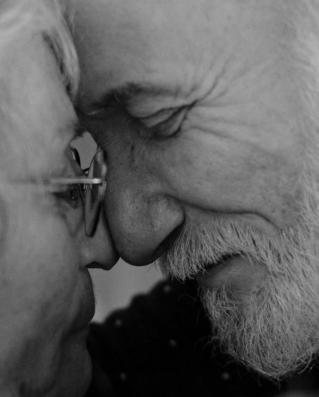 Close-up in black and white of an elderly couple touching noses, showcasing the intimate moment and details of aging.