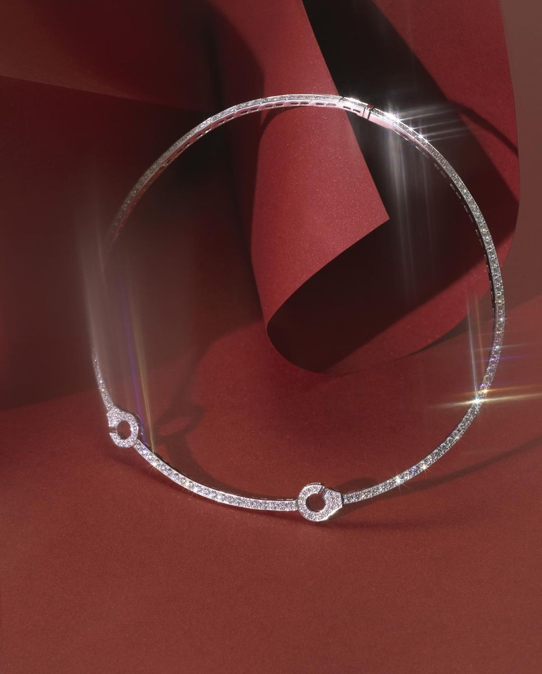 Elegant silver choker necklace with diamond embellishments on a red background with soft lighting for a sophisticated jewelry advertisement.