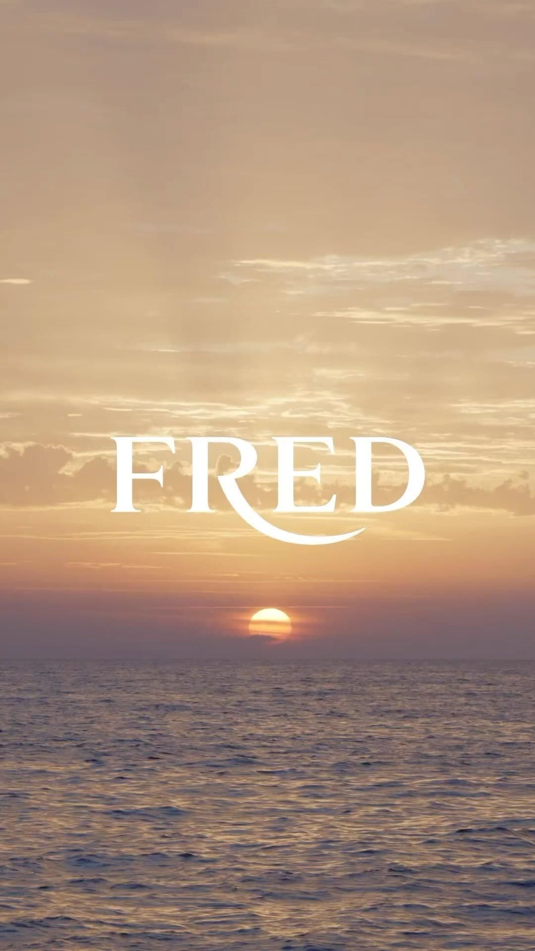 Scenic ocean view at sunset with a soft, golden sky and the word FRED in white lettering overlaying the horizon.