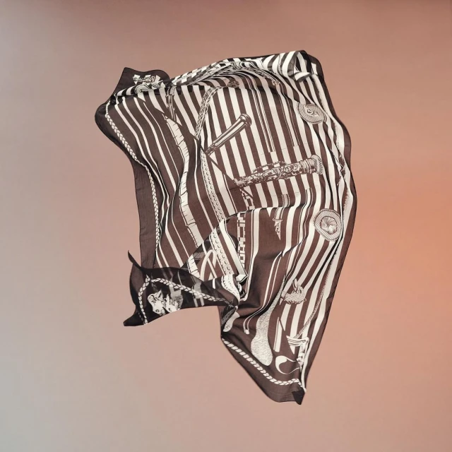 Silk scarf with nautical-themed print featuring stripes, ropes, anchors, and telescopes, floating in a studio setting with soft gradient background.