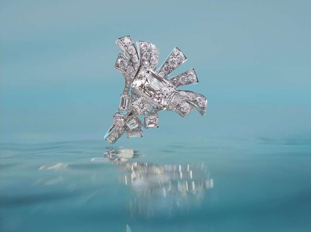 Elegant diamond jewelry piece with a ribbon shape and reflective surface, presented against a soft blue background for luxury visuals.