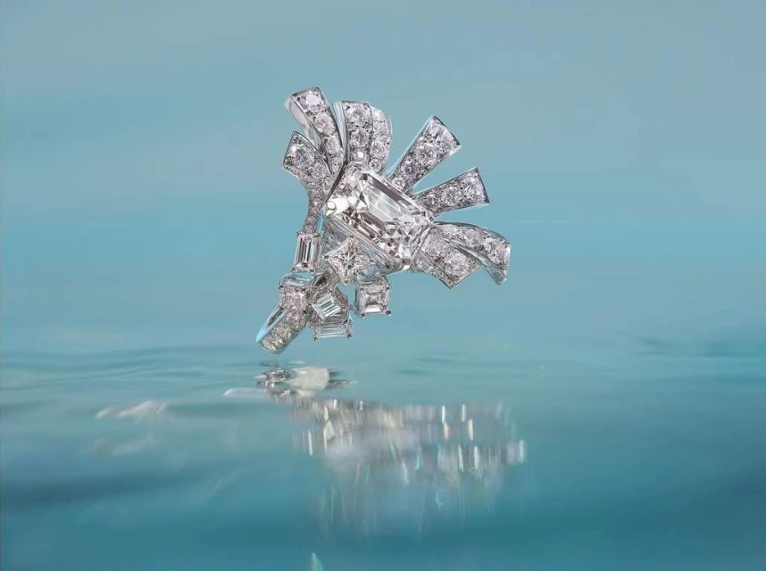 Elegant diamond jewelry piece with a ribbon shape and reflective surface, presented against a soft blue background for luxury visuals.