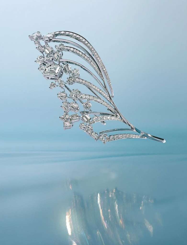 Sparkling diamond and platinum feather brooch. The brooch has a curved stem and is covered in diamonds. Set against a blue background.