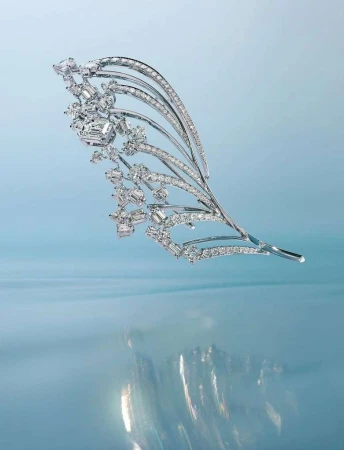 Sparkling diamond and platinum feather brooch. The brooch has a curved stem and is covered in diamonds. Set against a blue background.