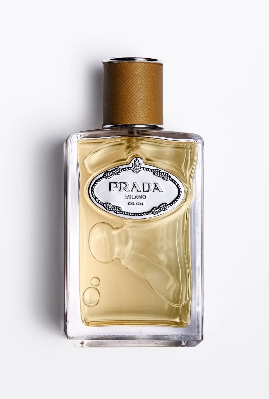 Close-up studio shot of a Prada fragrance bottle with a tan cap and clear glass, set against a bright white backdrop.