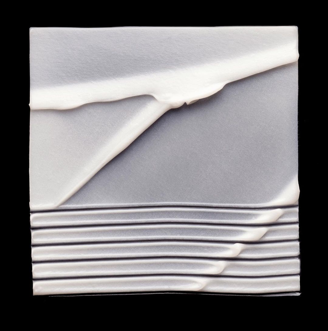 Abstract image featuring a gray textile with white and dark gray accents, presented against a stark black background. 